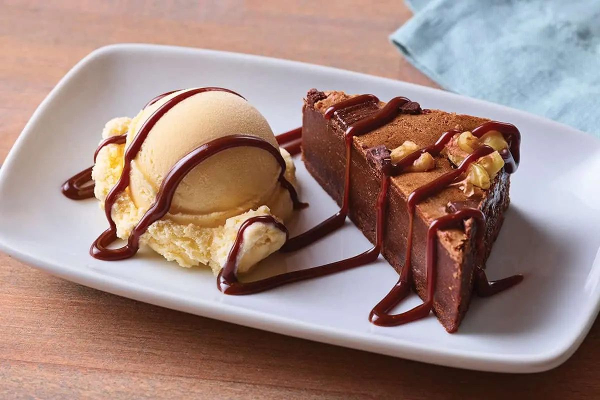 Fudgy brownie topped with a scoop of vanilla ice cream and rich chocolate drizzle.
