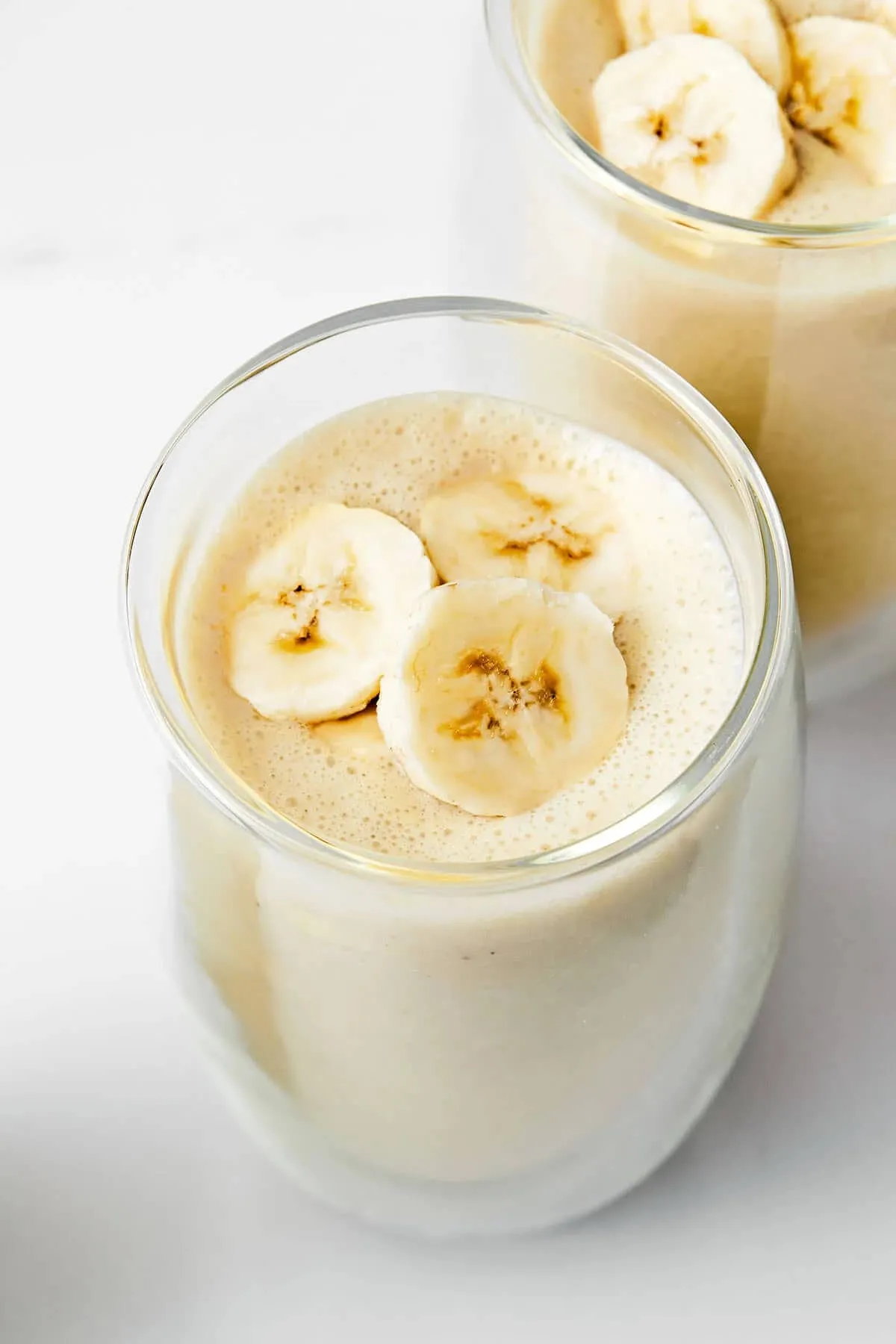 Thick banana smoothie in a glass topped with banana slices