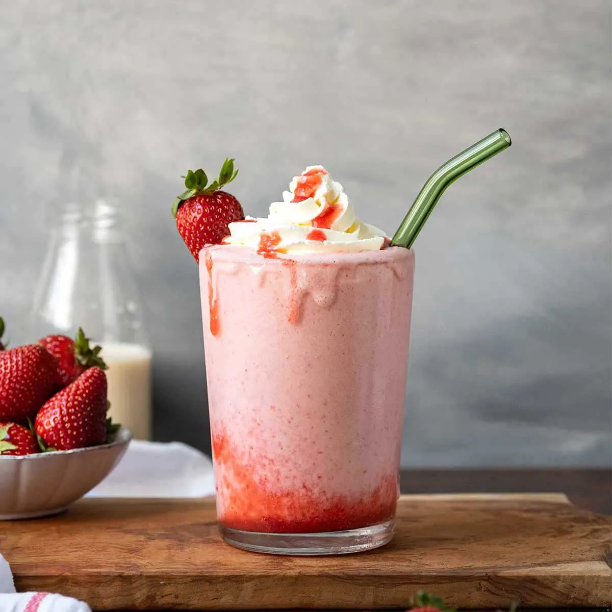Cold strawberry shake in a glass with whipped cream and ice